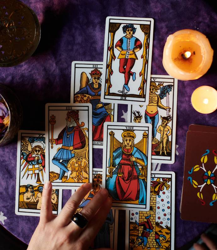 Close-up of a fortune teller reading tarot cards on a table with purple tablecloth